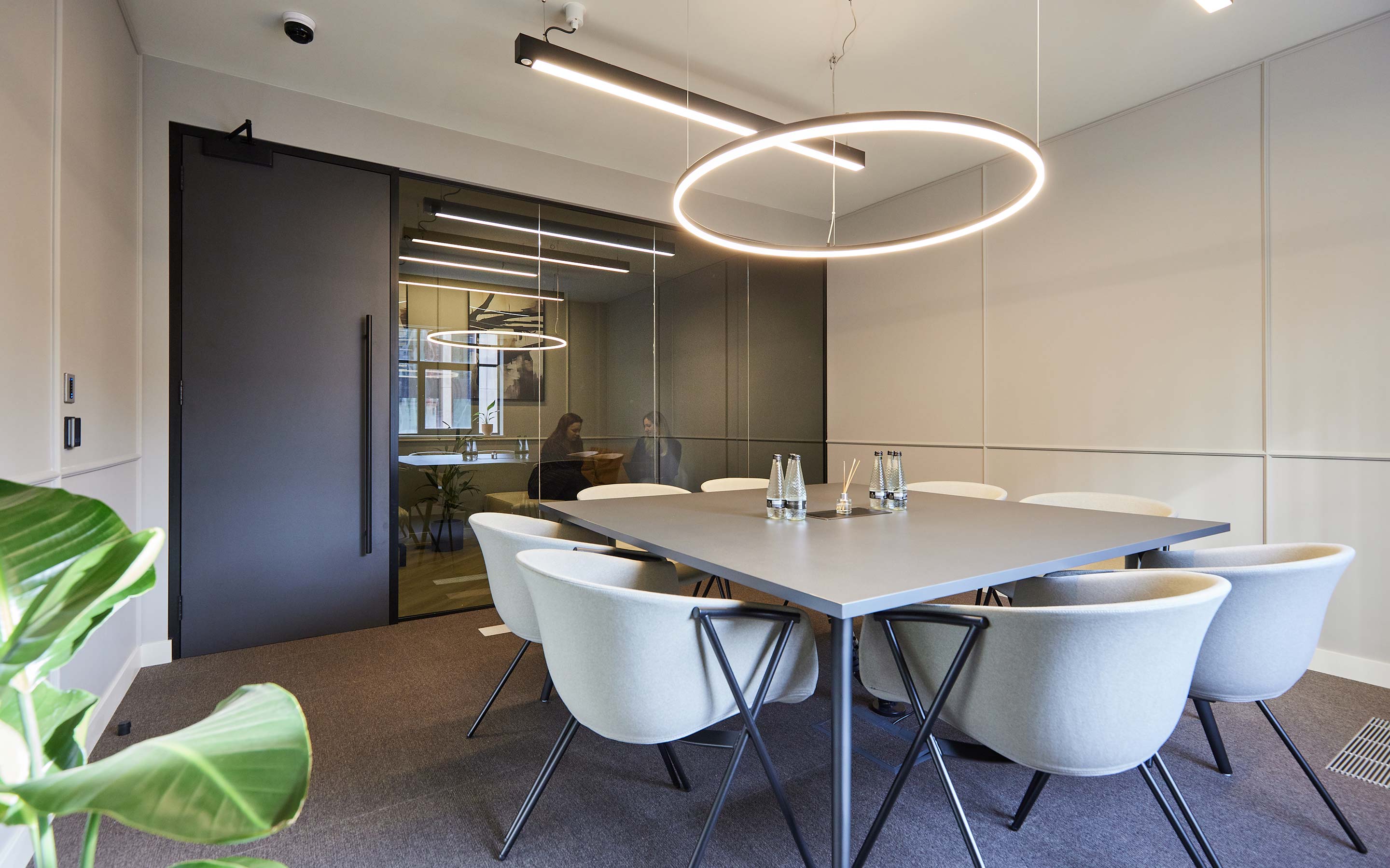 Sleek conference room in a London office interior design featuring smoky privacy glass and grey upholstered chairs