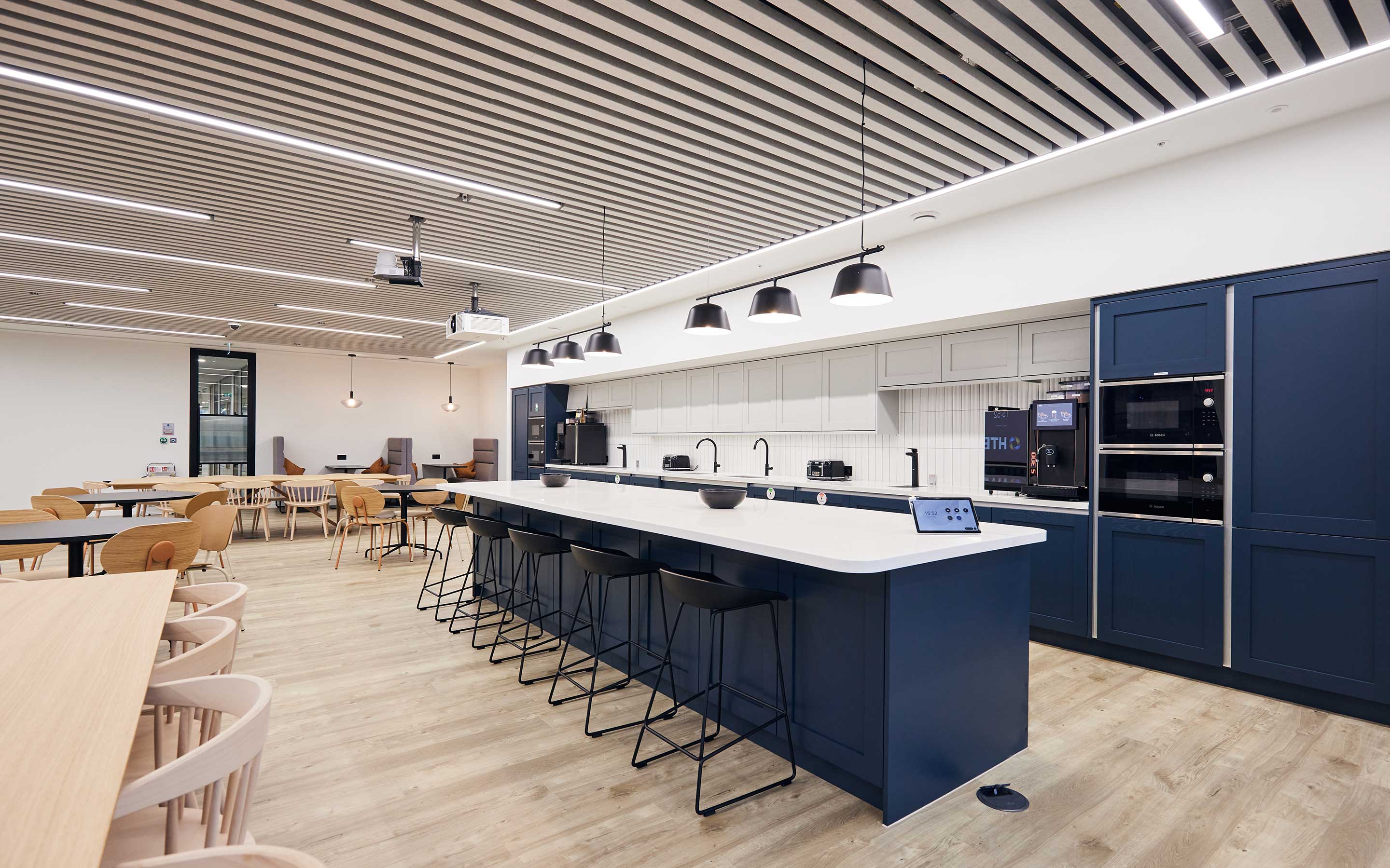 A spacious, bright office teapoint with navy cabinets, a breakfast bar and lots of seating for employees