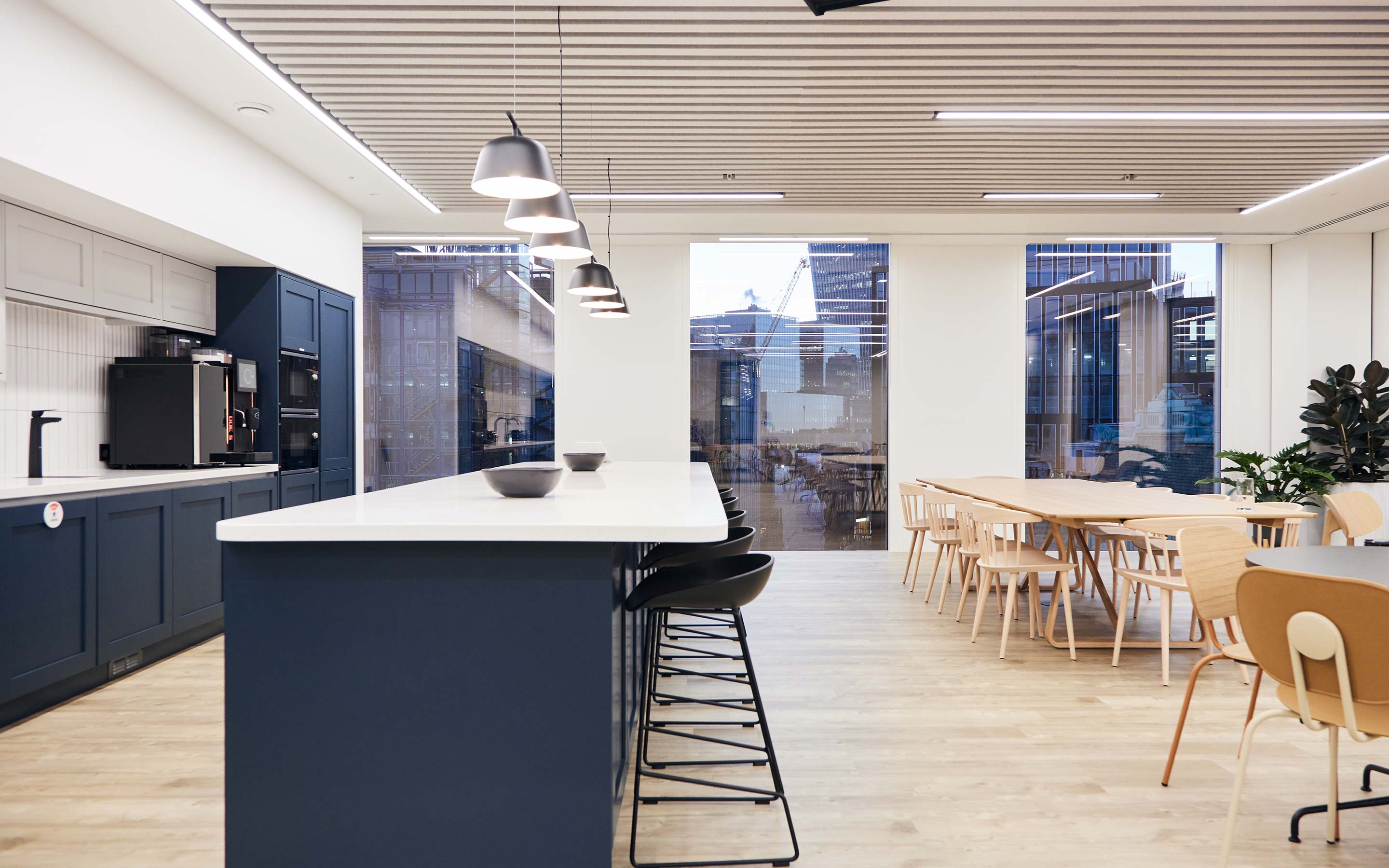 A spacious, bright office teapoint with navy cabinets, a breakfast bar and large wooden kitchen table