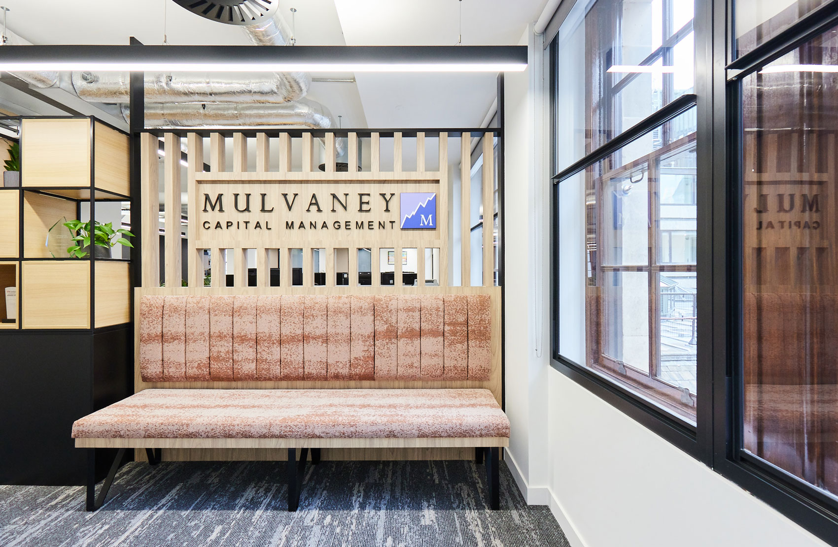Company logo atop bespoke joinery in a contemporary office reception area
