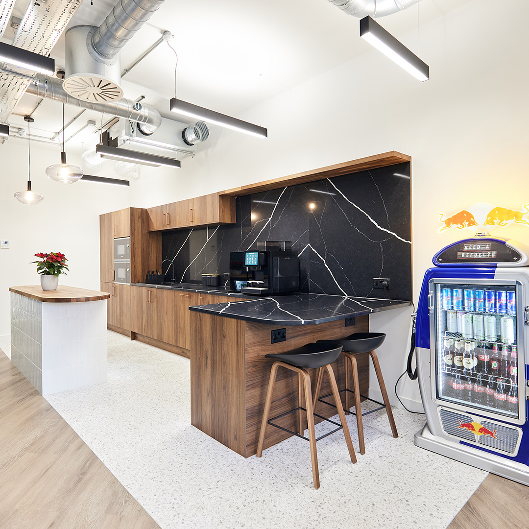 Office interior design showcasing a teapoint with black marble countertops, breakfast stools and high, bright ceilings