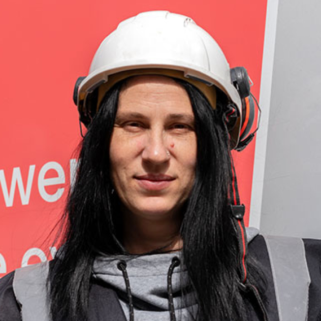 Employee wearing a safety hat in a black jacket on site