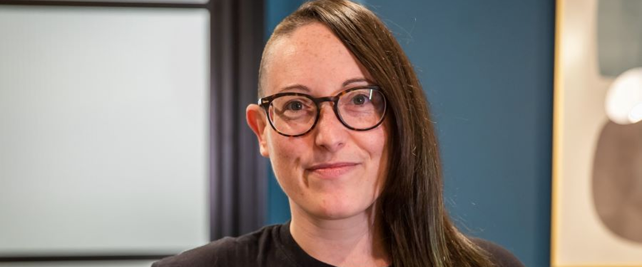 corporate headshot of a brown-haired woman with glasses