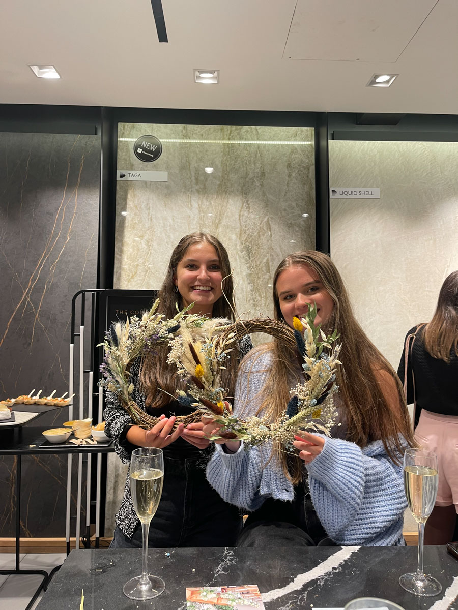 Two girls holding a designed wreath