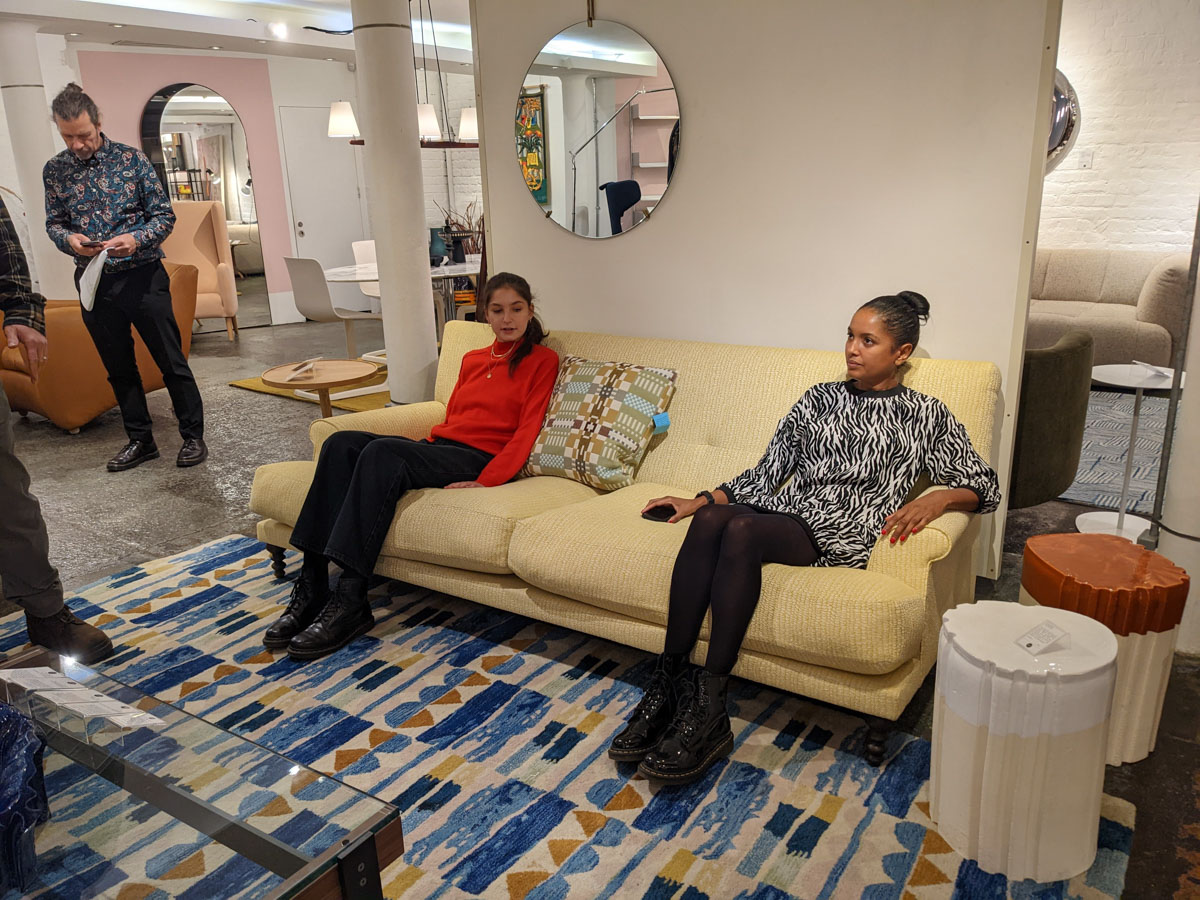 Two women at a furniture showroom sitting on sofa