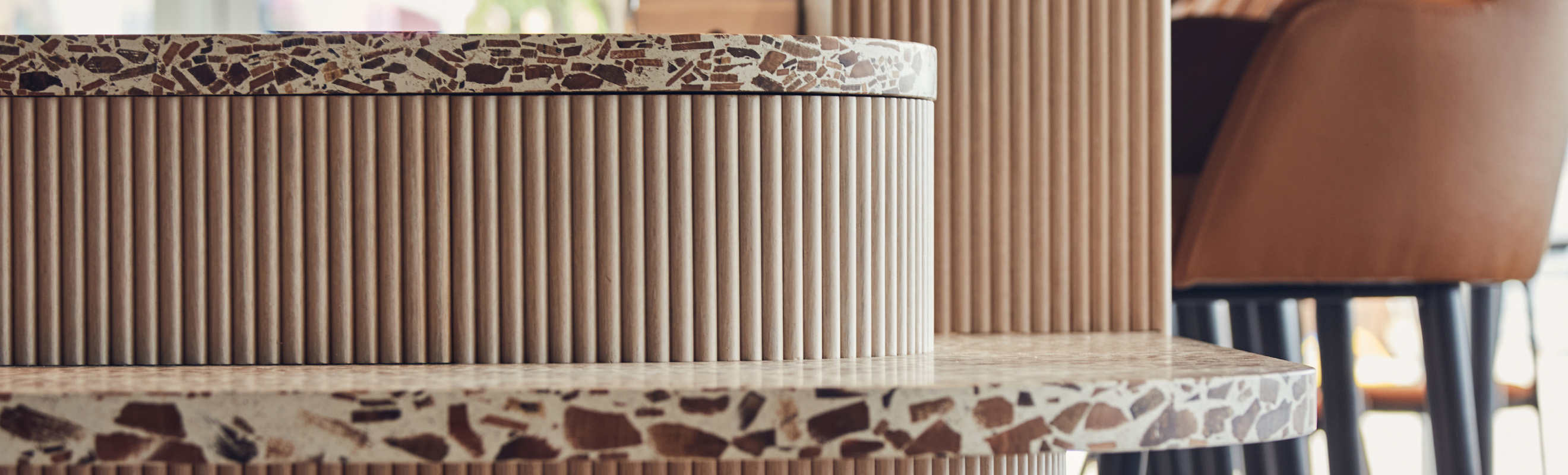 Detail shot of brown terazzo worktop with brown leather seating