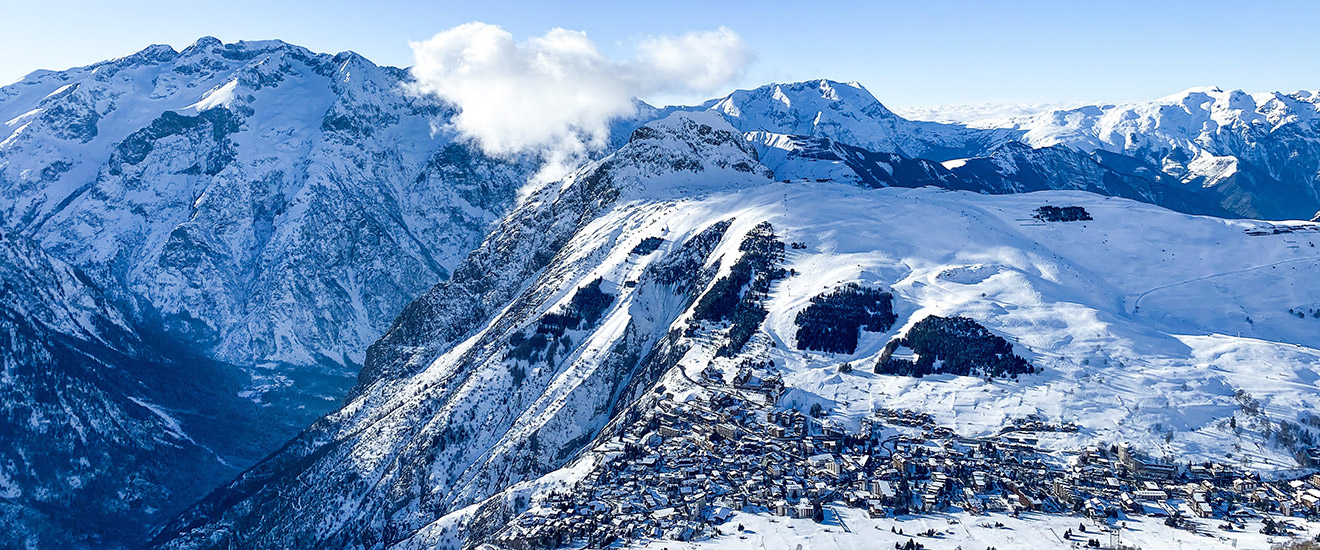 Snow capped mountain range with groups of trees and houses