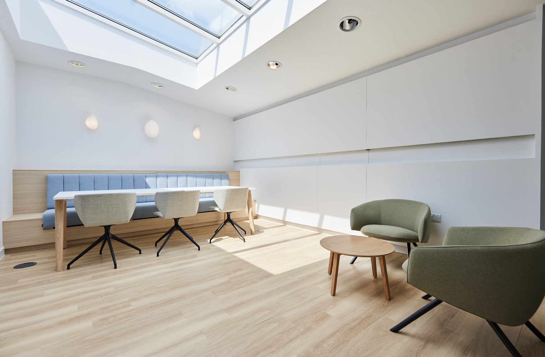 An office reception area features a large skylight, banquette seating, and a coffee table and chairs