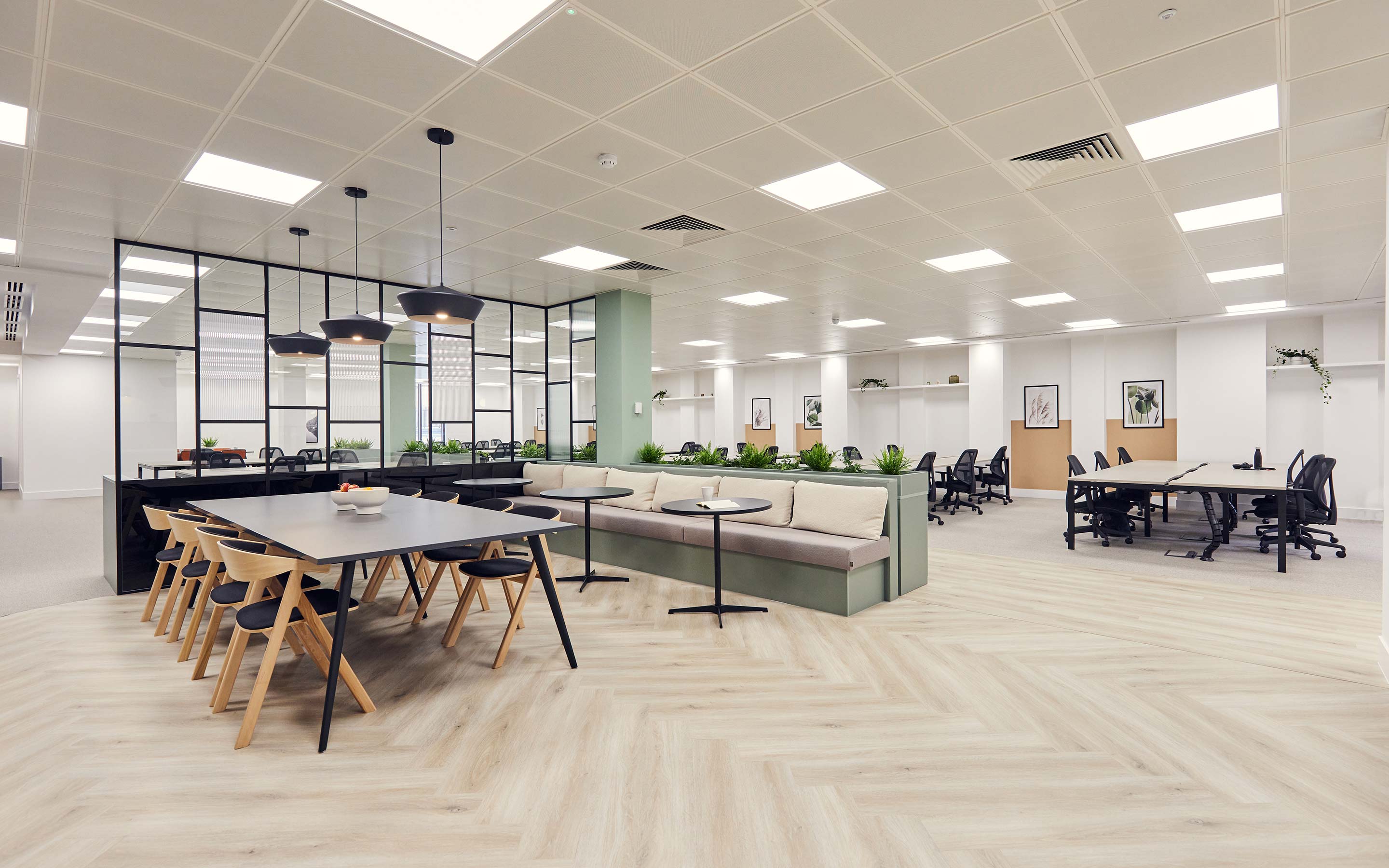 The image features an open plan office and teapoint with an array of seating options, including a kitchen table and chairs, traditional office desks, and banquette seating