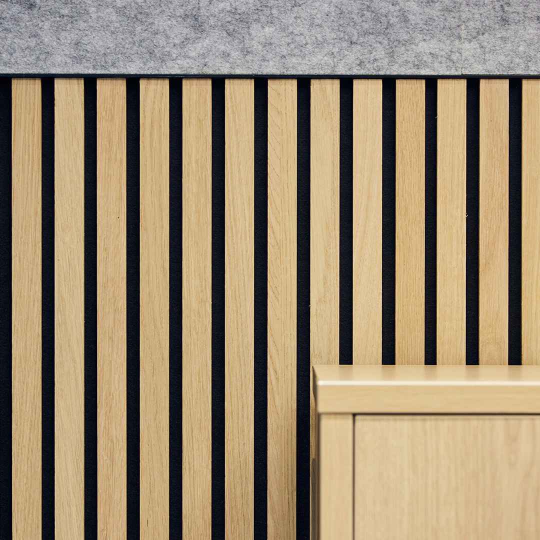 The image is a detail shot of acoustic wall fabric and bespoke wooden joinery in an office meeting room