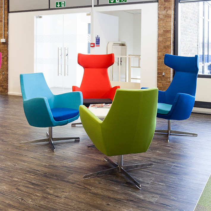 four multicoloured high backed chairs all facing inwards towards a central white table within an open space