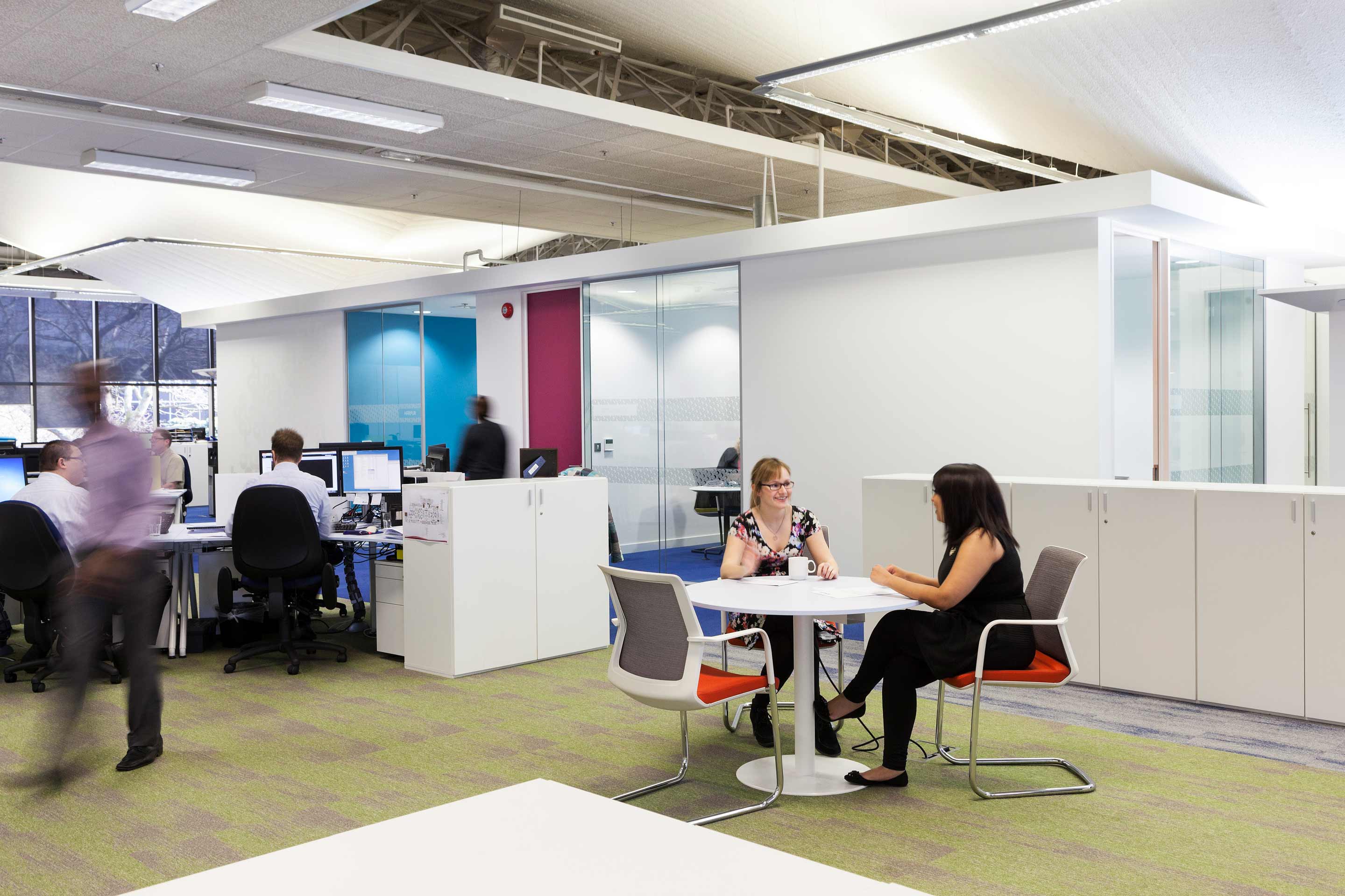 Two women talking on a white table in an open plan workspace