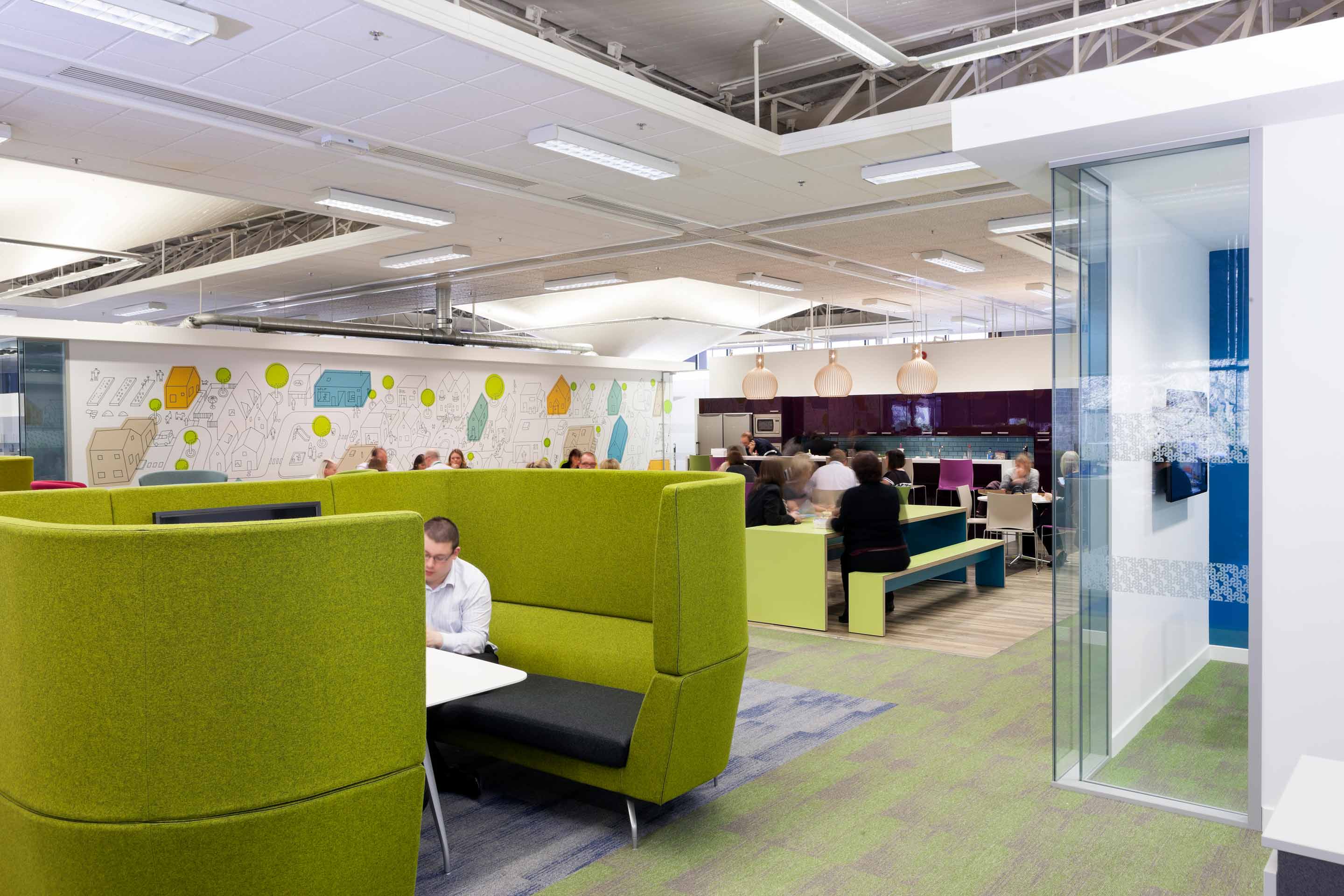 An open plan kitchen and work desk space with a white graphic wall