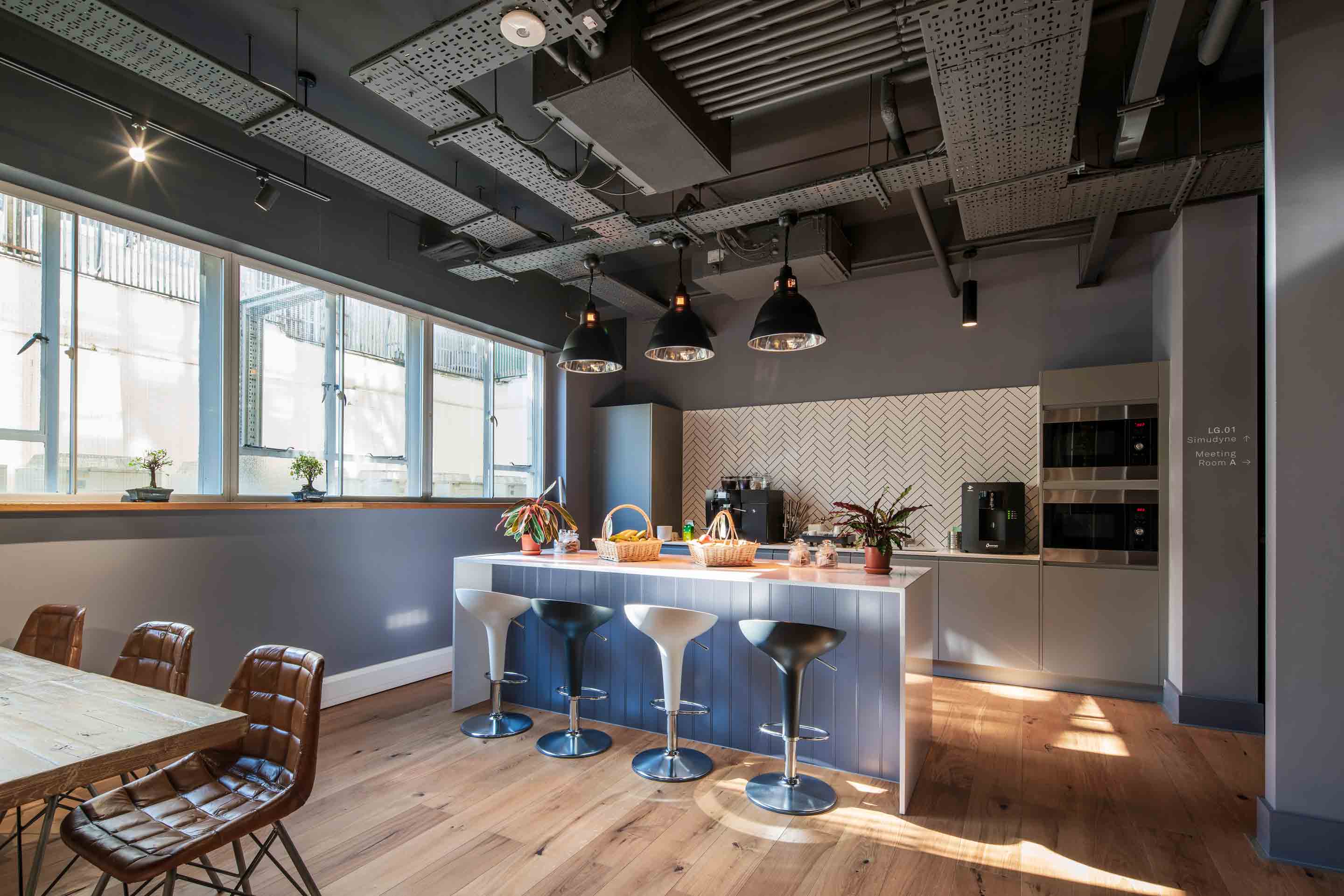 workspace kitchen area with bar stools and plants