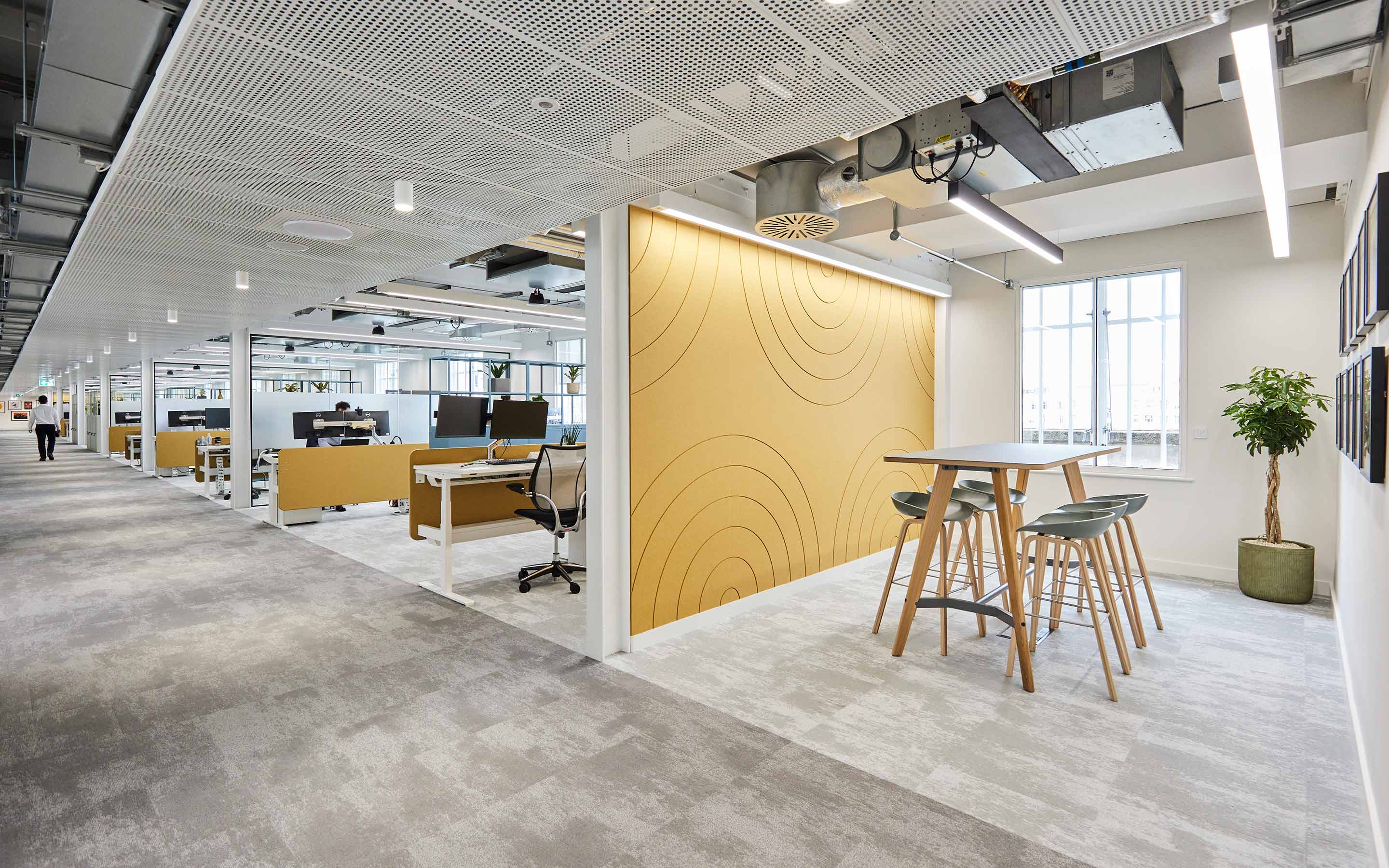 A collaboration area, complete with a high table and stools, acoustic panels and a yellow wall