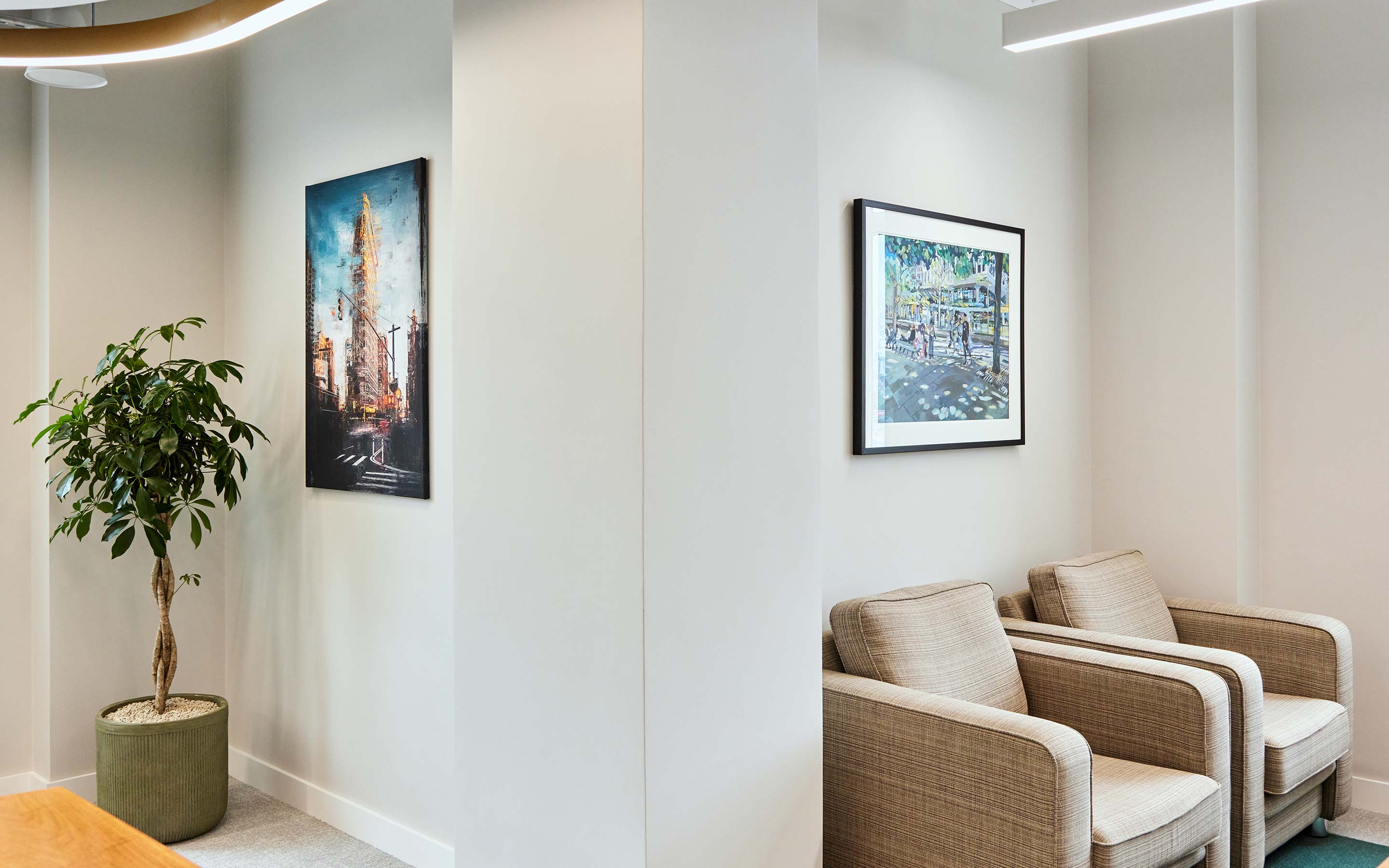Artwork hangs above two office armchairs in a meeting room