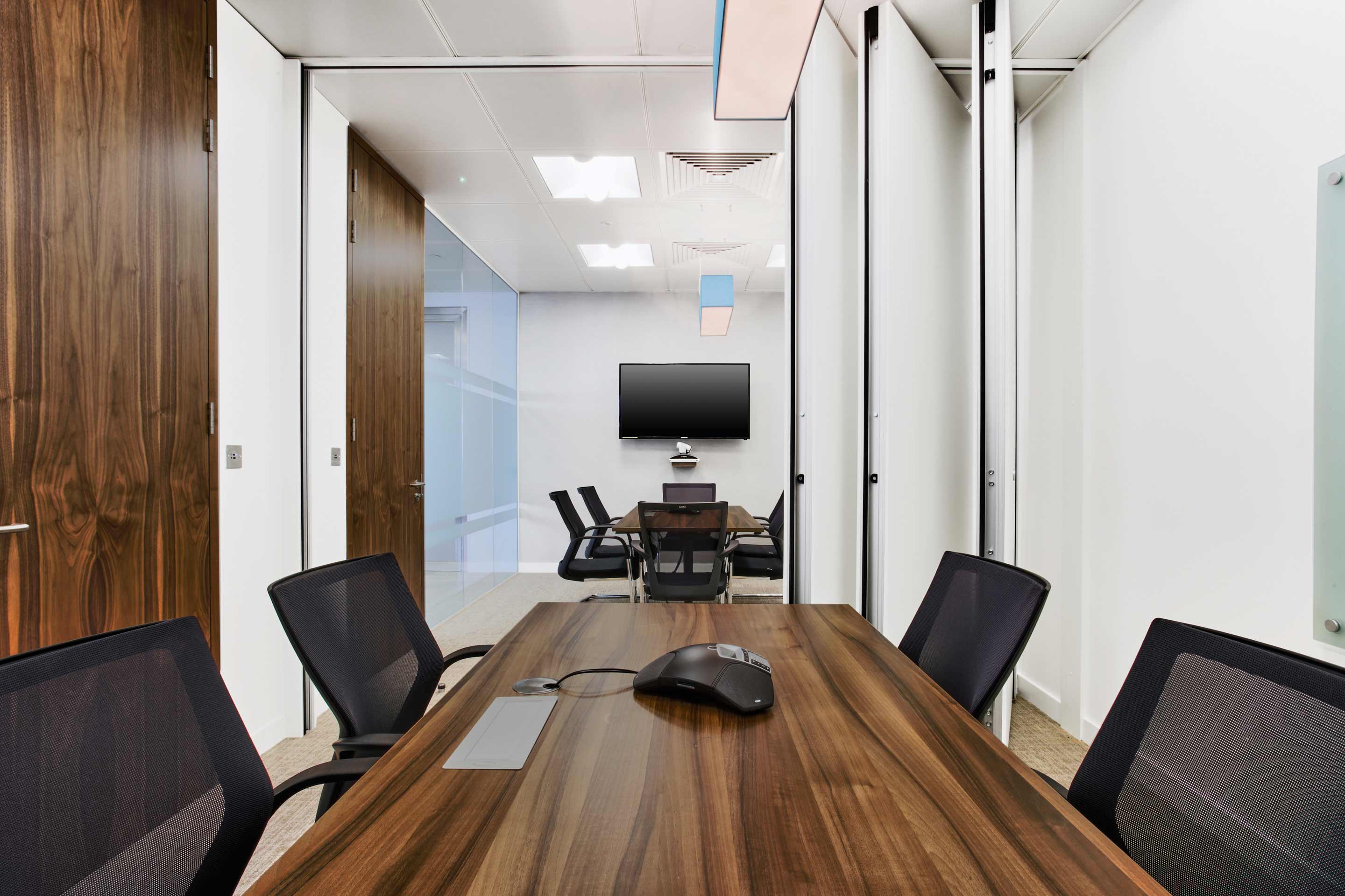 Meeting room with a partitioned wall and a small dark wooden table and chairs