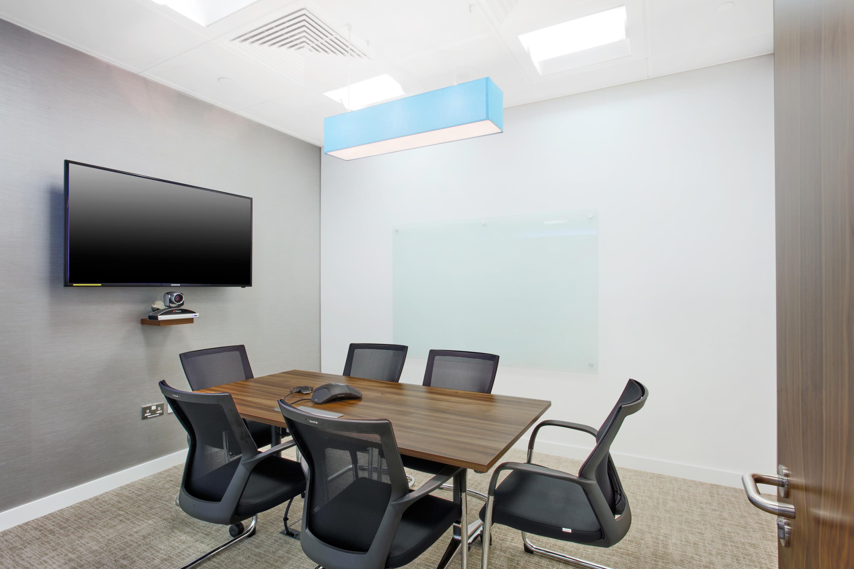 Meeting space equipped with a TV and dark wooden table and chairs