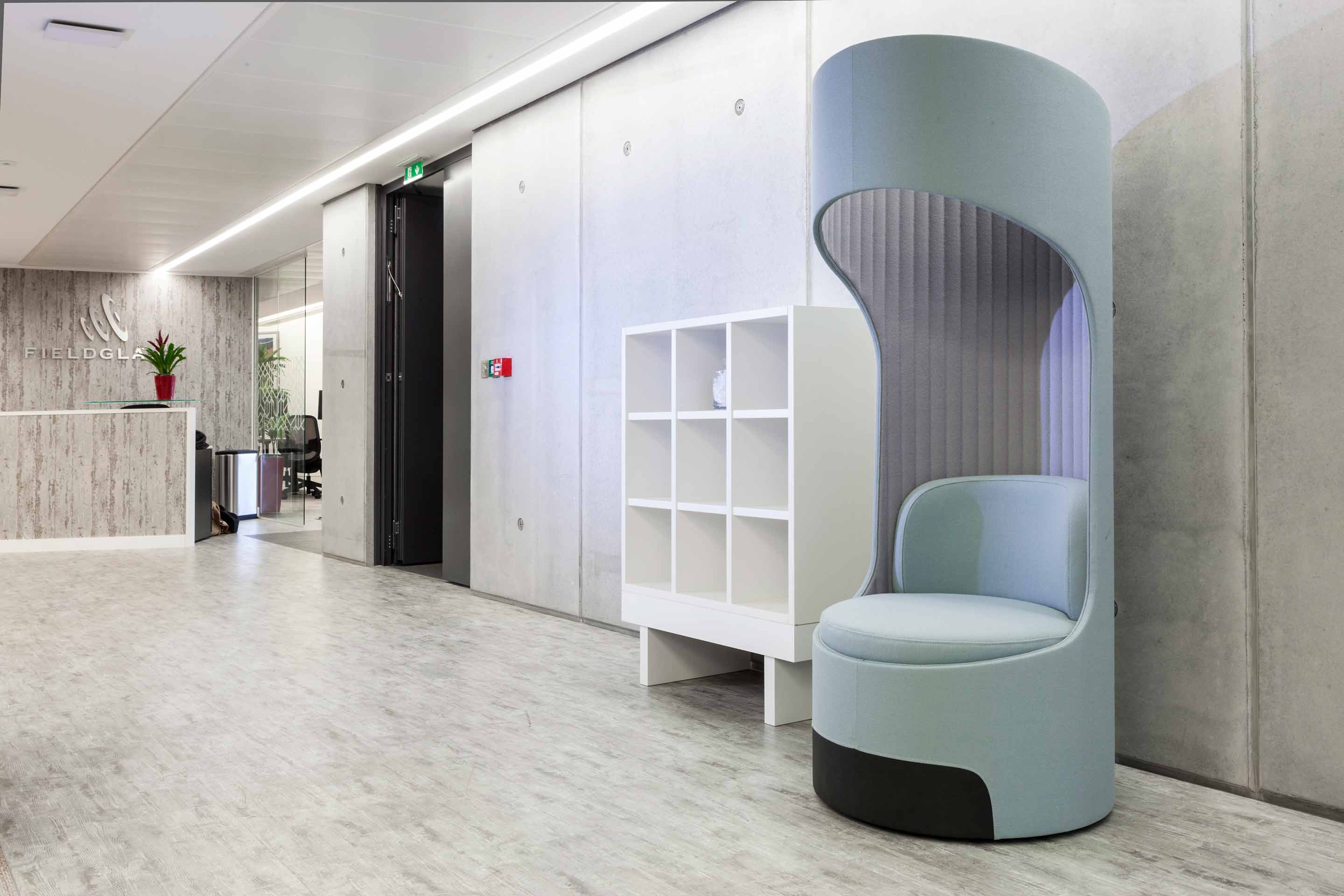 A light blue single seat pod with a white square bookcase to the left and a grey wood effect front desk on the opposite side