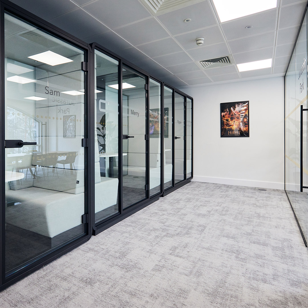A sleek corridor showcasing a modern office interior design, complete with phone booths and film posters