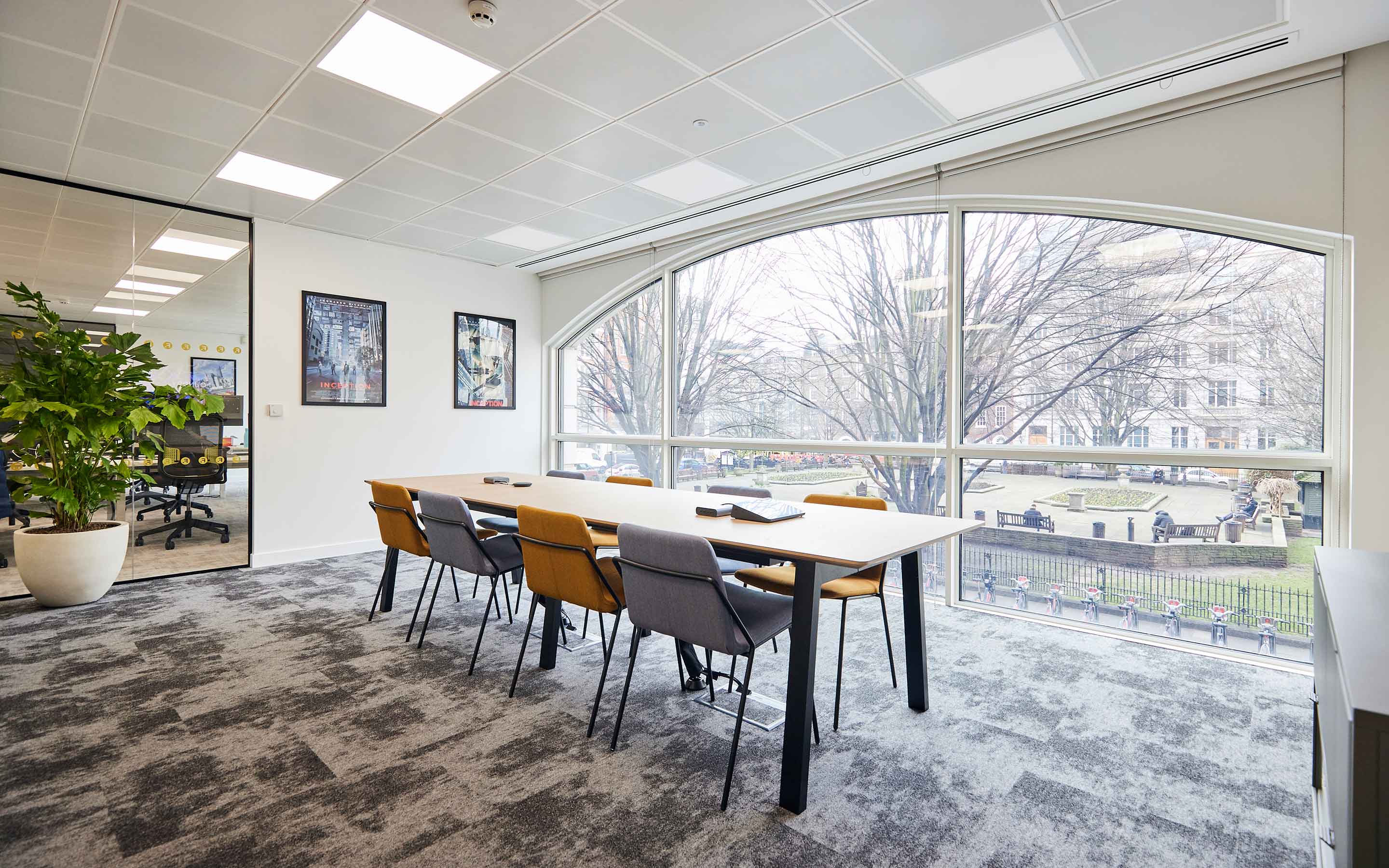 A well-designed office space featuring a large window, a table, and chairs, ideal for meetings and work in a professional environment