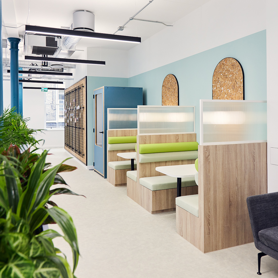 The image shows two meeting booths and tables in a bright office