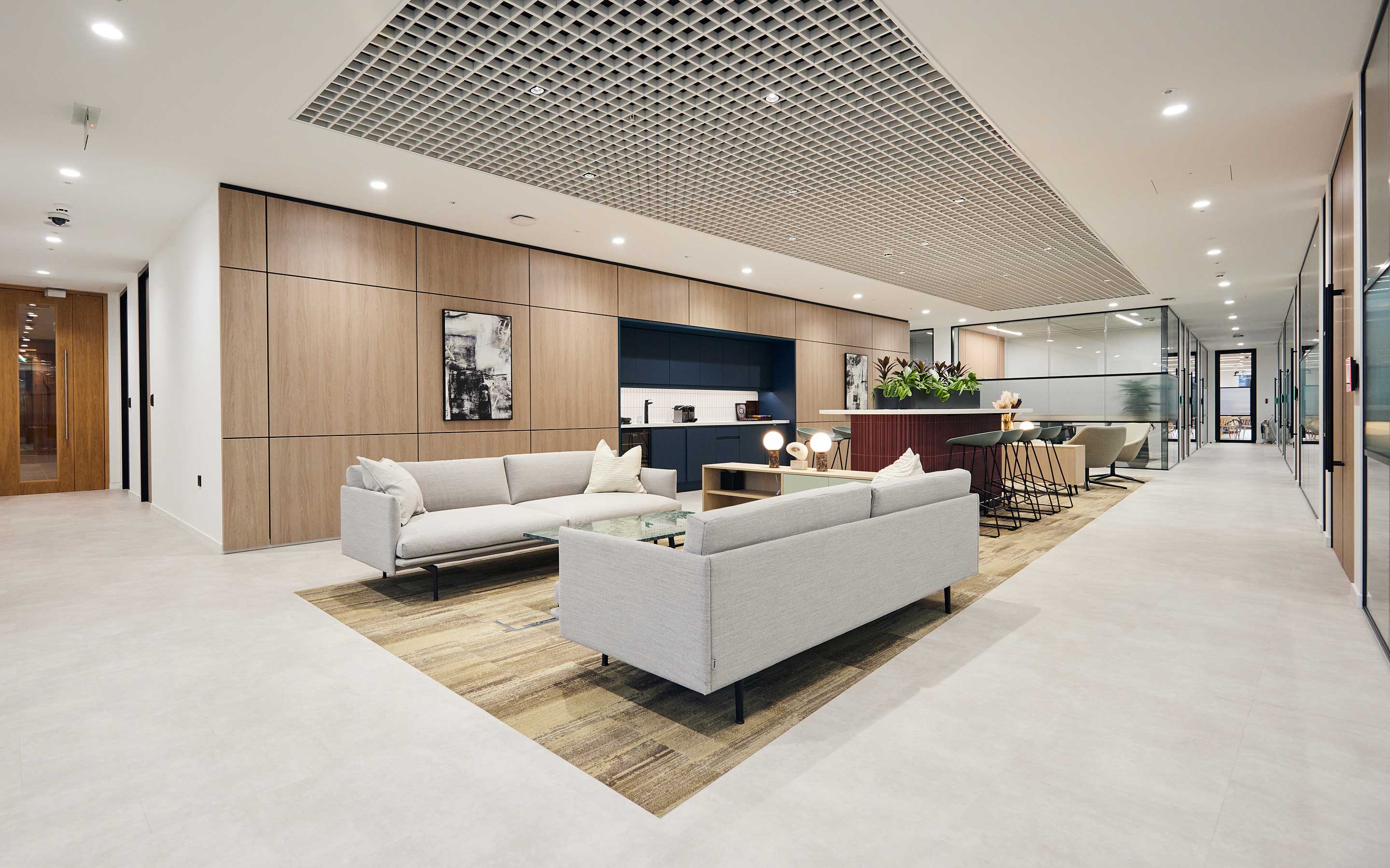 Sleek client waiting area in high-end London office with soft furnishings, bespoke joinery, and plush carpets