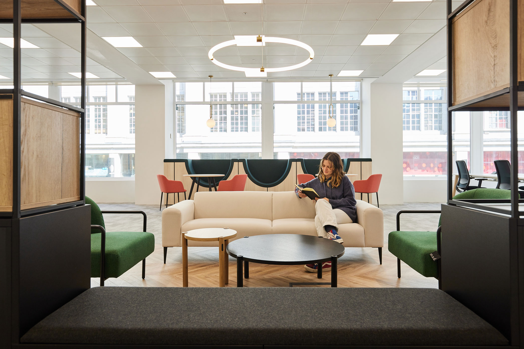 Social seating in a London office interior design with a woman reading a book