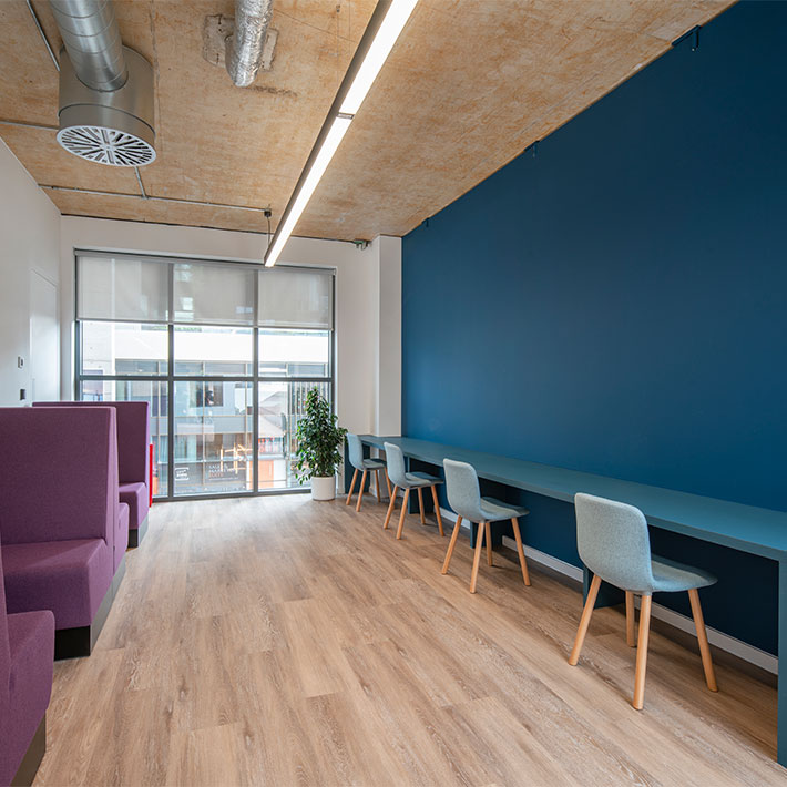 Quiet working area in a commercial office space with soft, colourful seating and blue wall