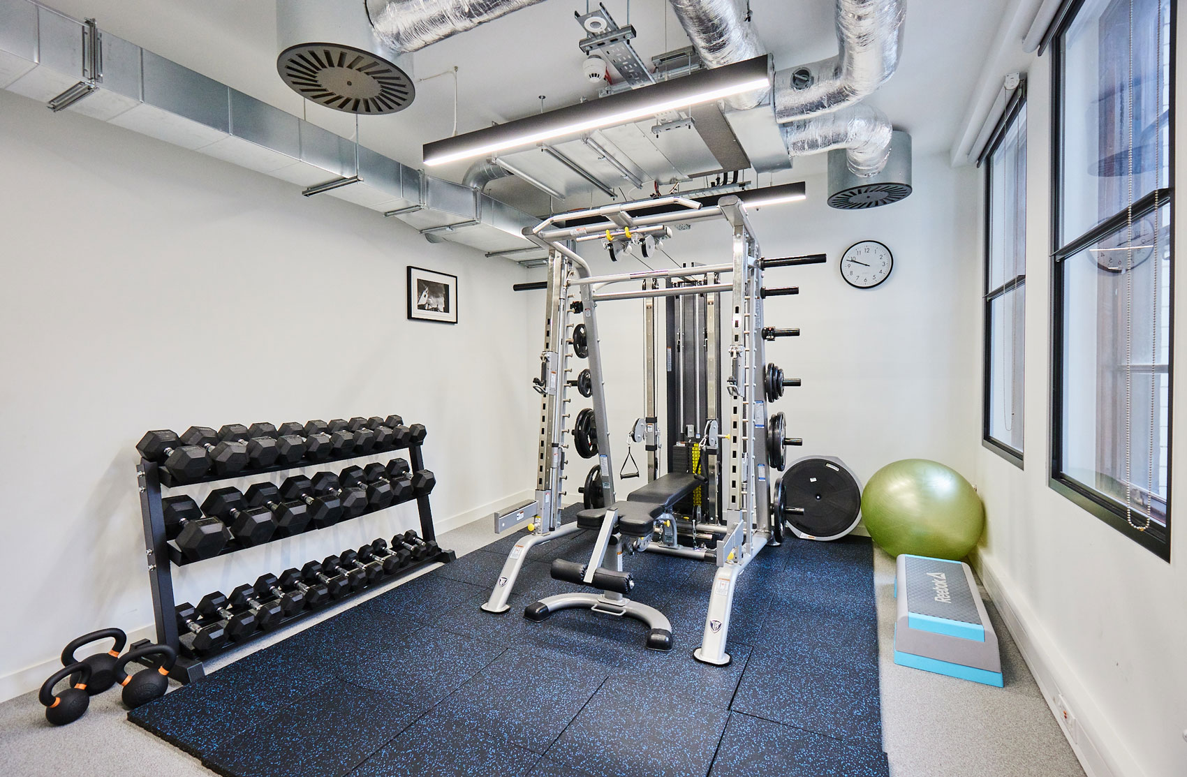 Office gym complete with a weight rack and exercise balls, promoting wellness and activity at work