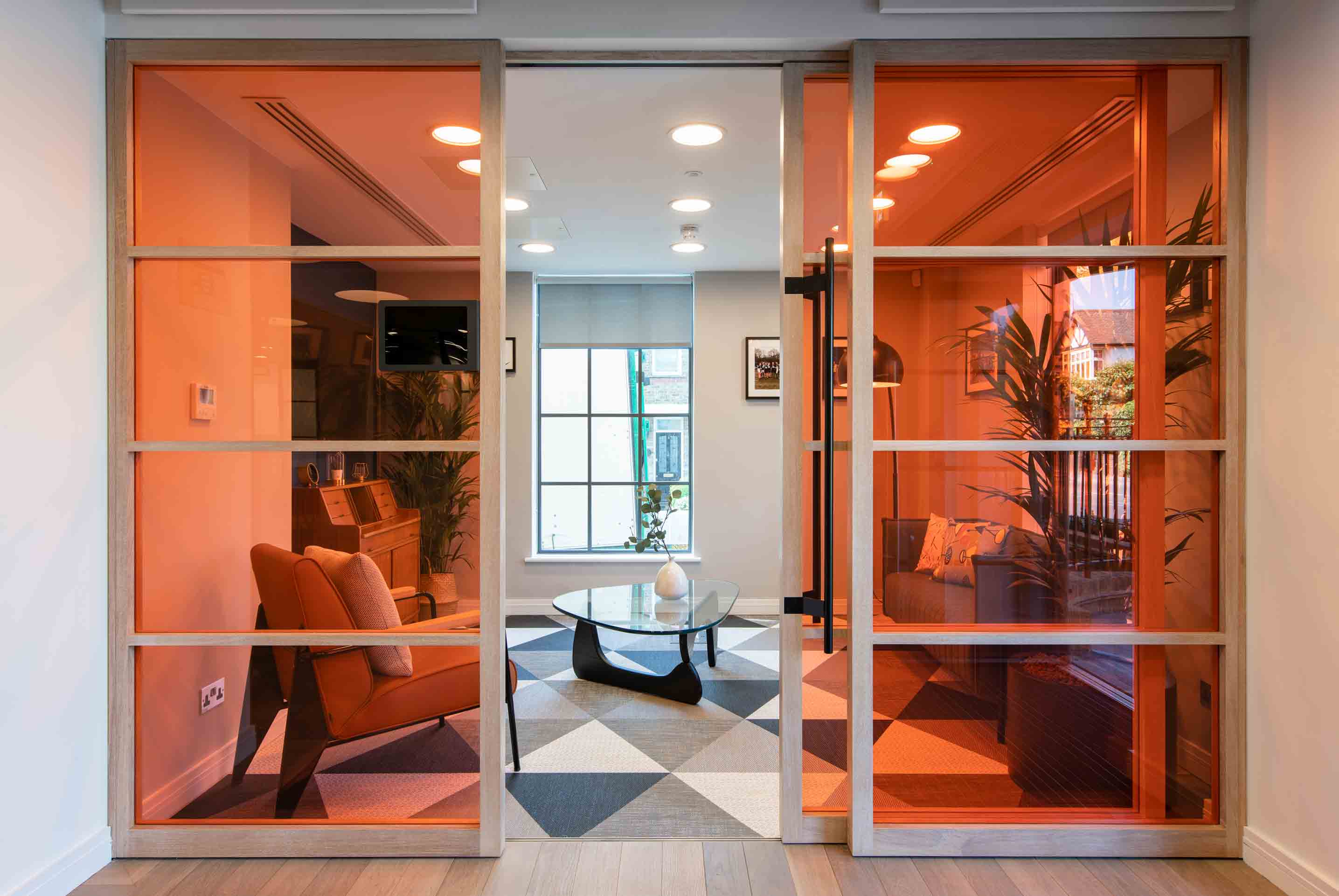 bright meeting room with plants, soft seating and orange glass doors