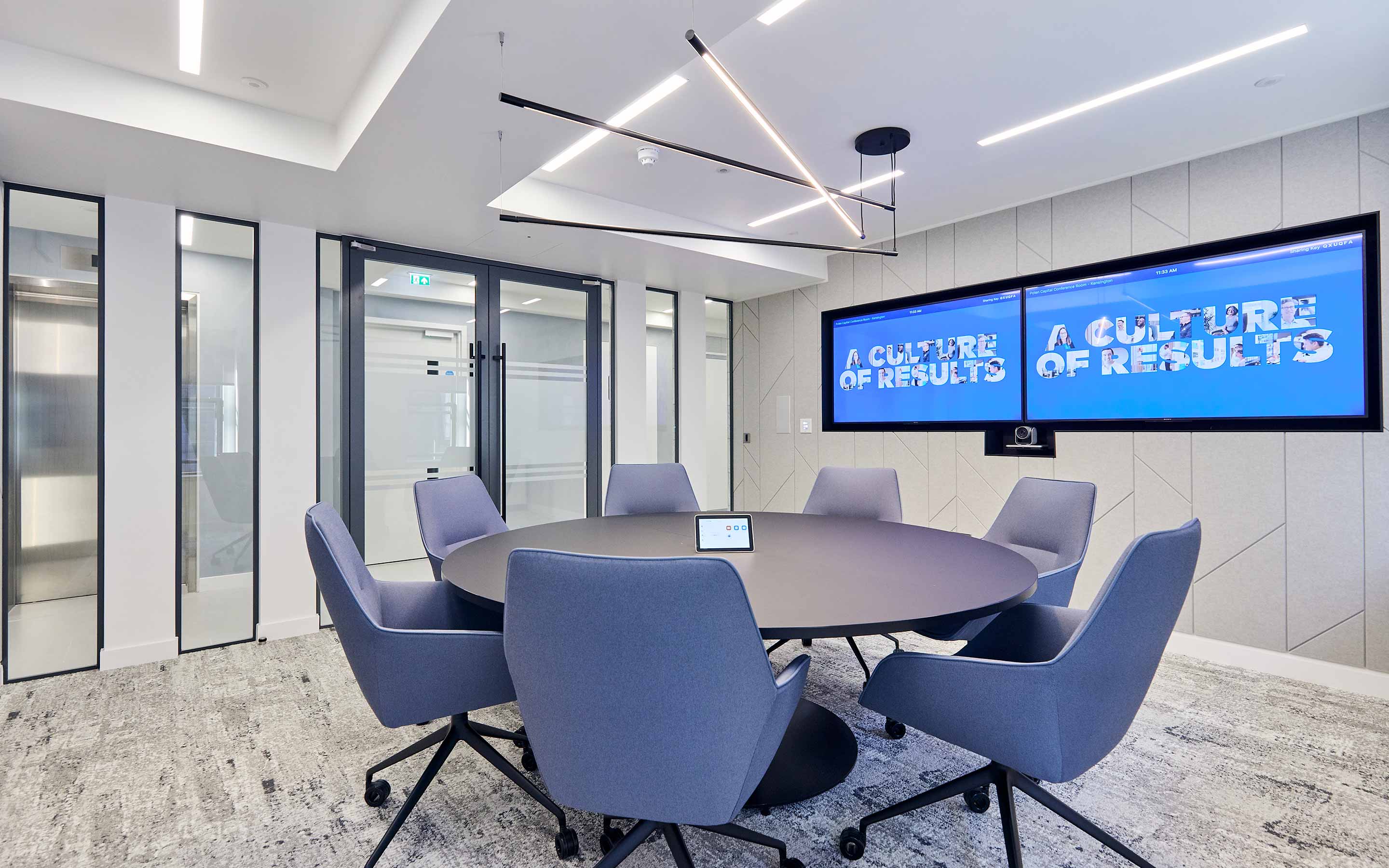 Office conference room featuring bright blue chairs and a large screen for meetings in workplace setting