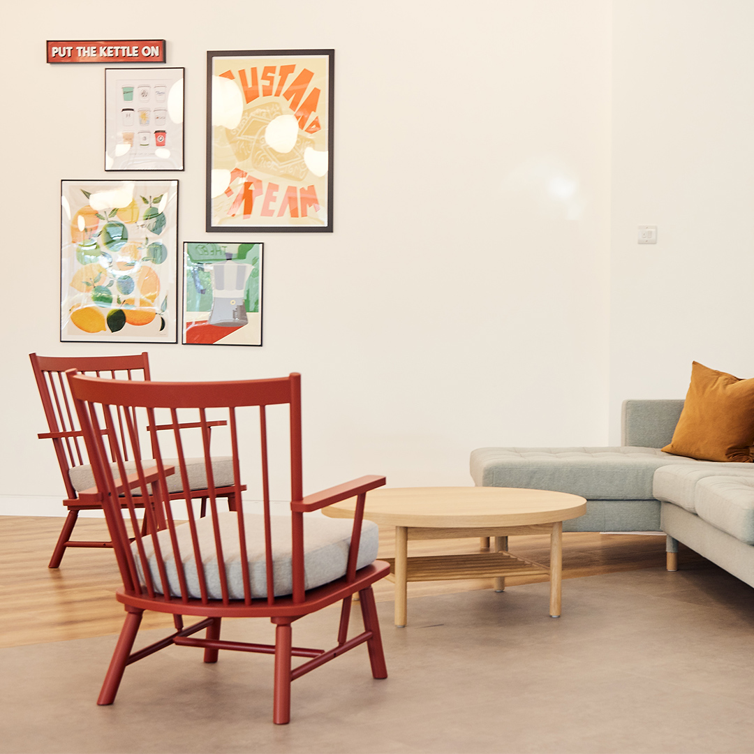 Soft seating in an office breakout space with a couch, chairs, and vintage artwork