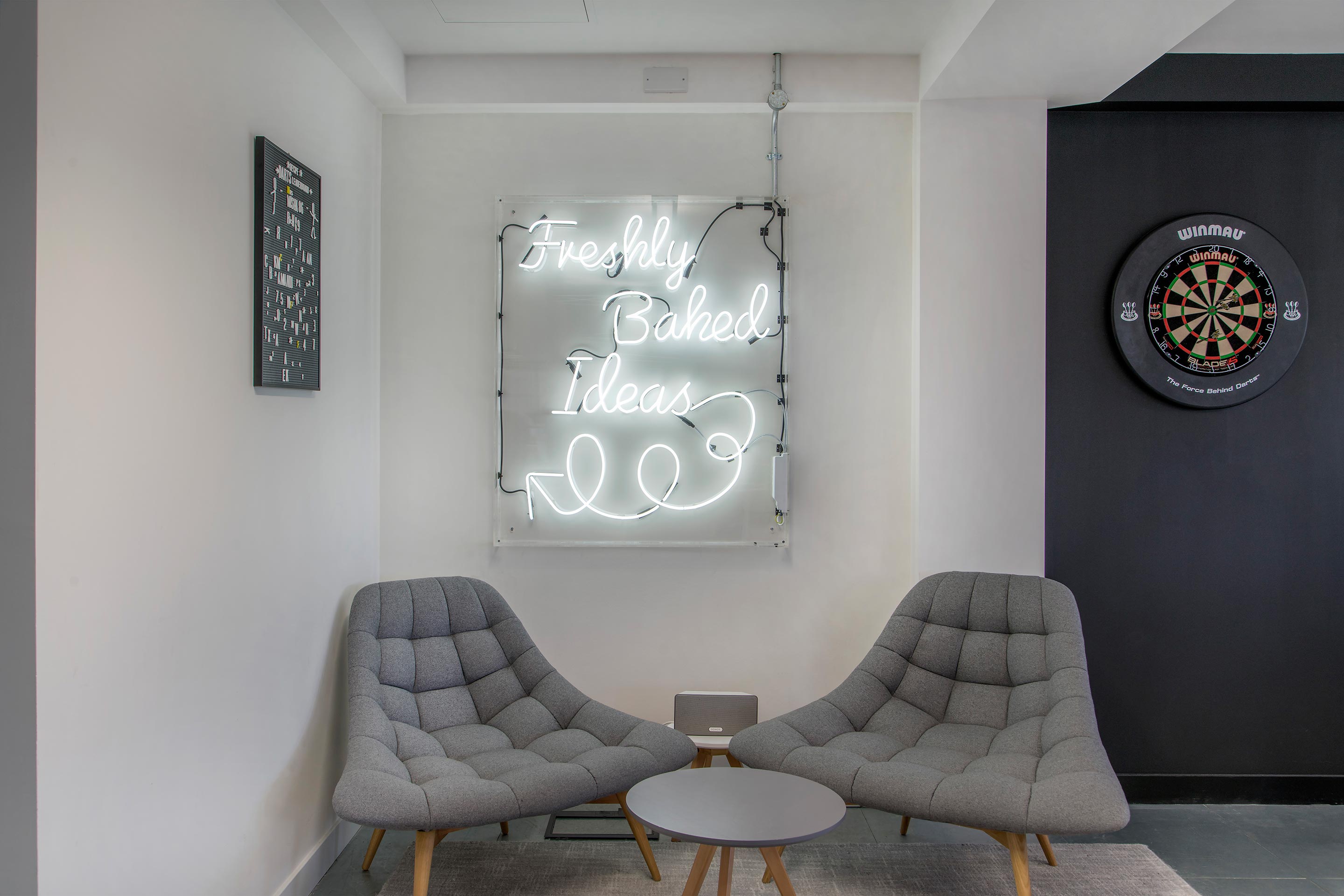Soft seating and neon signage in Recipe's office