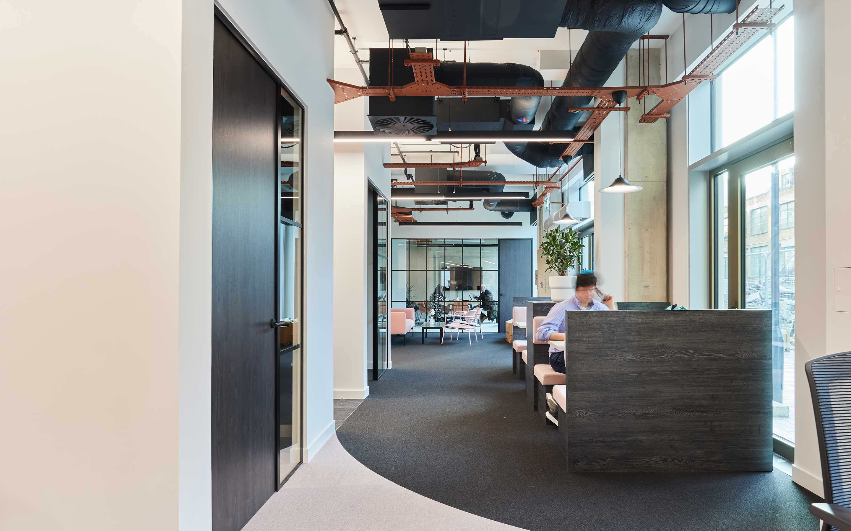 The image shows views of meeting booths in a office, with curved floor detailing and warehouse style design