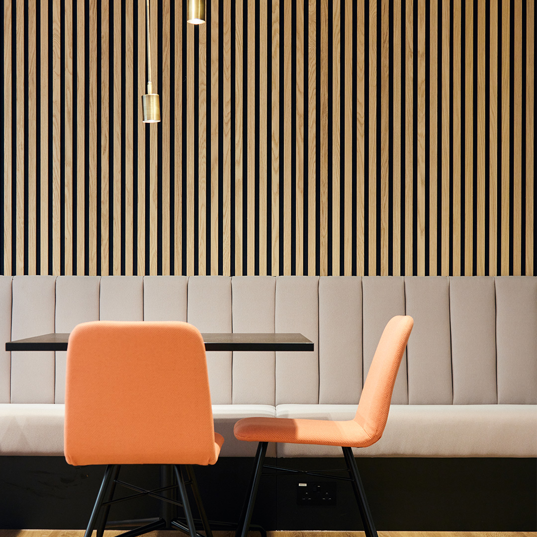 Office interior design with vibrant orange and pink chairs and a sleek table