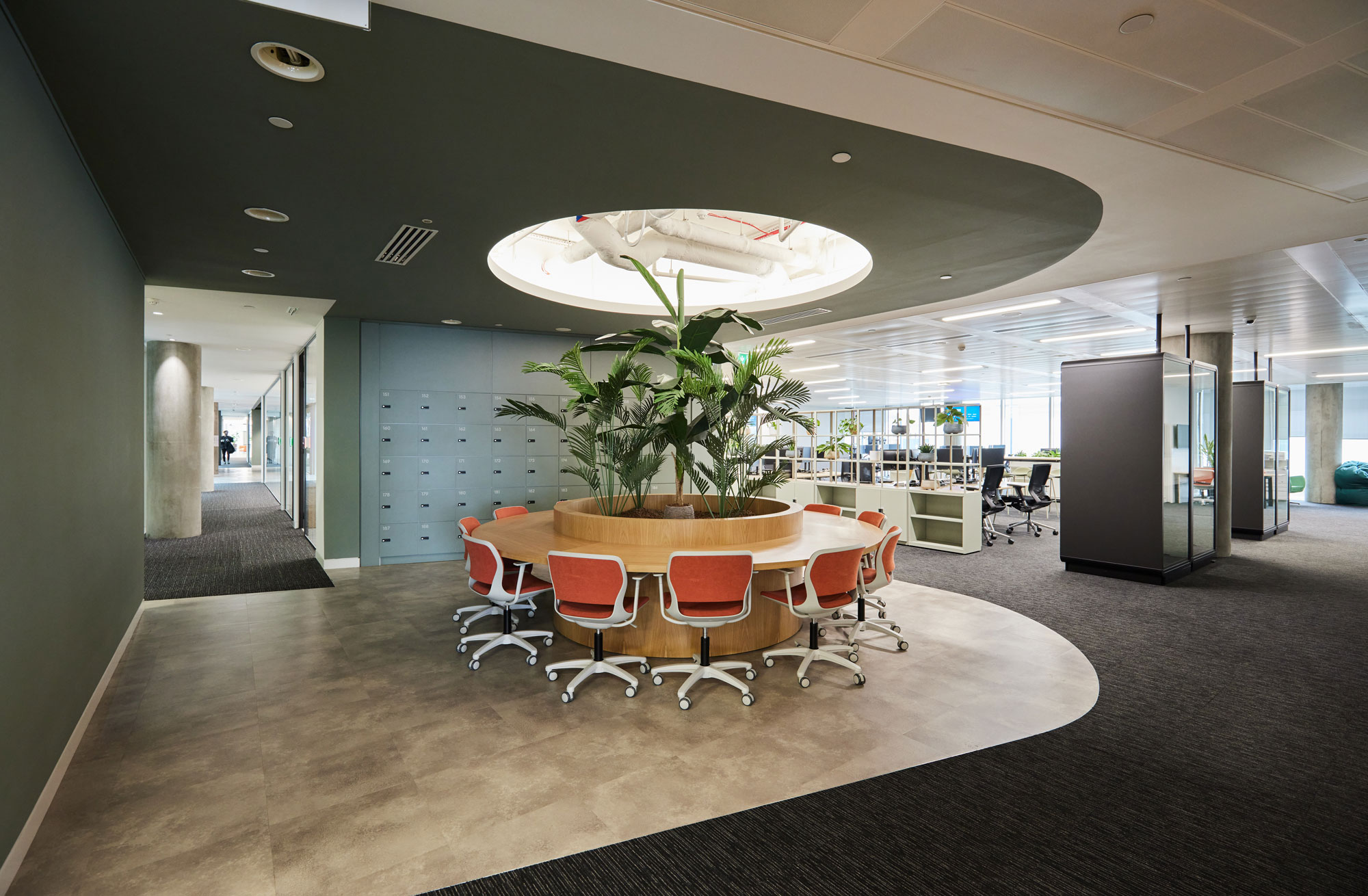 Open plan office with central collaborative working area, dressed with flourishing greenery