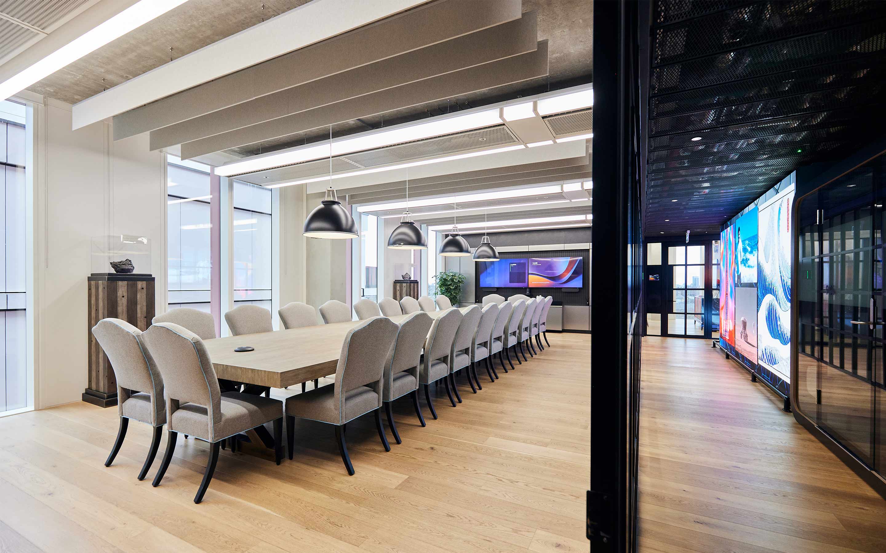A modern boardroom with sleek furniture, large conference table, high-tech presentation equipment, and elegant lighting fixtures
