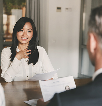 Woman sitting across from an interview candidate. She is holding a resume.