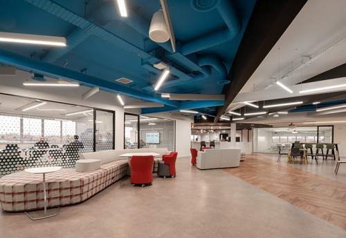 An open place office space with a large sofa to the left and a collaboration area to the right