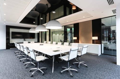 Large white boardroom table with suspended lighting