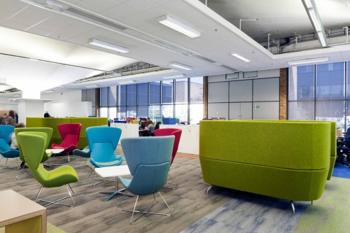 multi coloured high backed seats on the left with larger green fabric sofas on the right within an open plan workspace