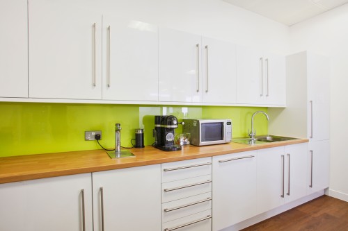 A white kitchen space with a green backsplash