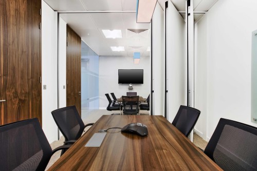 Meeting room with a partitioned wall and a small dark wooden table and chairs