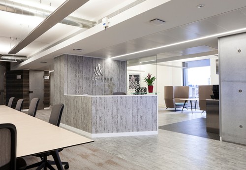 A front desk with a greyscale wood effect in the centre of an open plan seating space filled with natural light